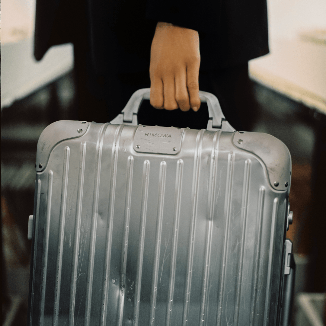 Person holding silver Rimowa Suitcase